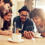 Group of Friends Surrounding Phone at Cafe